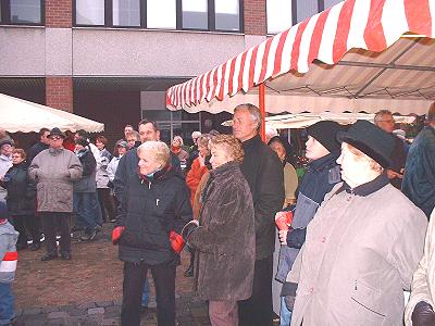 Besucher auf dem Weihnachtsmarkt 2005 in Schwarzenbek vor der Bühne mit Musikzug und Jugendblasorchesterk